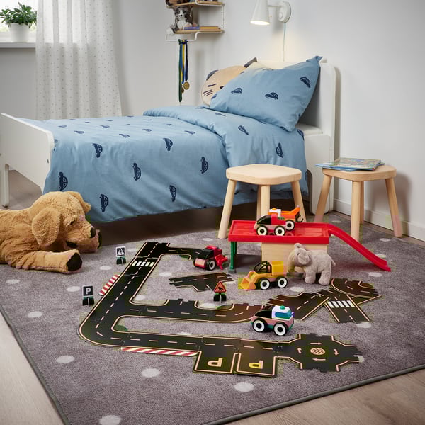 Childs play area with car bedding, toys, mat, stool. Alternative: kids car-themed play area with toys, mat, stool.