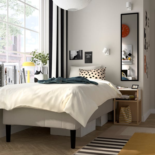 Modern bedroom with a RÅHOLMAR white bed, polka dot pillows, black-and-white decor, and large window.