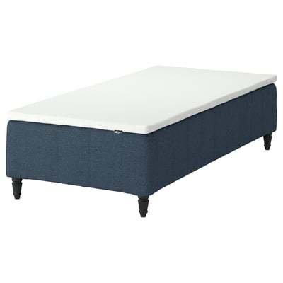 This image shows a blue fabric-covered bed base with wooden legs and a white mattress on top. It combines stylish design with comfort.