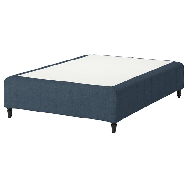This image the IKEA RÅHOLMAR bed base in dark blue, with a rectangular shape and four wooden legs. It supports a white mattress.
