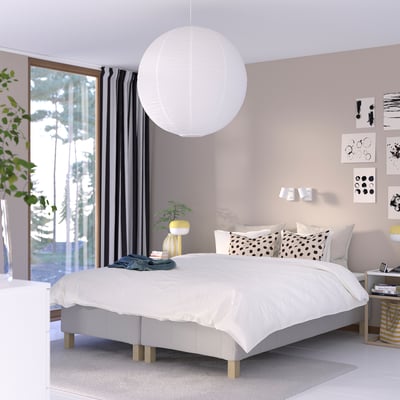Modern bedroom with white RÅHOLMAR bed, plant, side table, pendant lamp, and garden view.