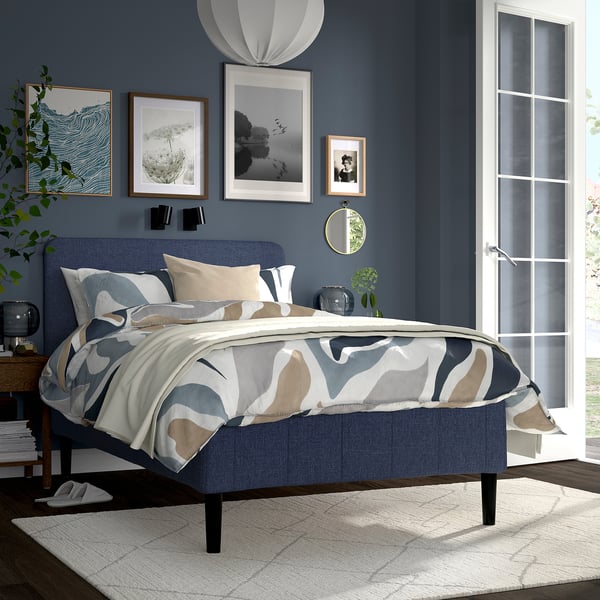 Minimalist bedroom with blue bed, dark blue walls, mirror, and white french door.