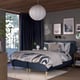 Modern bedroom with gray RÅHOLMAR bed, wooden floor, large window, dark curtains, abstract art, pendant light, rug, nightstands, and shoes.