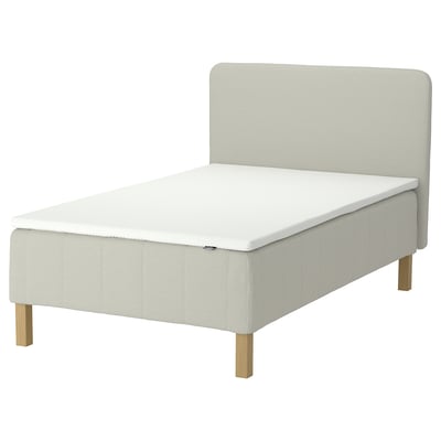 An IKEA RÅHOLMAR bed in white, featuring a padded headboard, wooden legs, and a memory foam mattress topper.