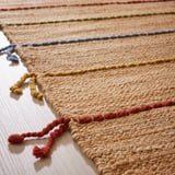 Colorful, handwoven jute rug with vibrant wool tassels, showcasing high-quality craftsmanship.