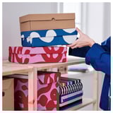 Organizing fabric boxes on wooden shelf.