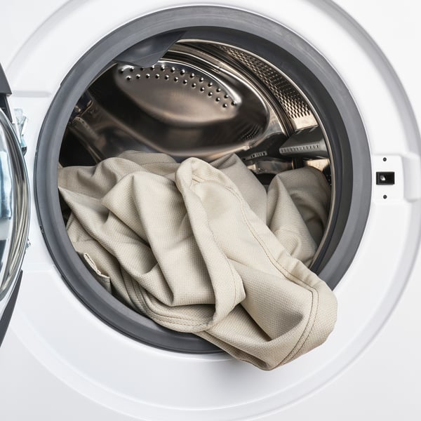 White washing machine drum with beige fabric cover, ready for a wash cycle.