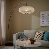 Modern living room with REGNSKUR lamp, beige shade. Grey sofa with cushions, white coffee table, and artistic wall decor.