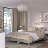 Bedroom with RENFJÄLLET bed, neutral tones, patterned bedding, large window, hanging lamp, wall art, and bedside table.