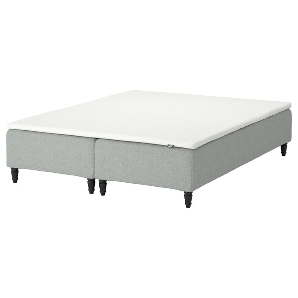 A light grey fabric-covered bed base with wooden legs, featuring a white, cushioned top surface, designed for comfort and support.