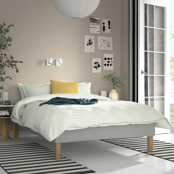 RENFJÄLLET bed with checkered white spread, yellow pillows, minimalist design.
