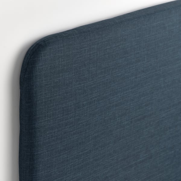 Close-up of a neatly tailored, dark blue bed headboard; smooth fabric, clean edge detailing.
