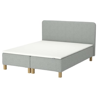 Alleviating; light grey bed with wooden legs and a padded headboard.