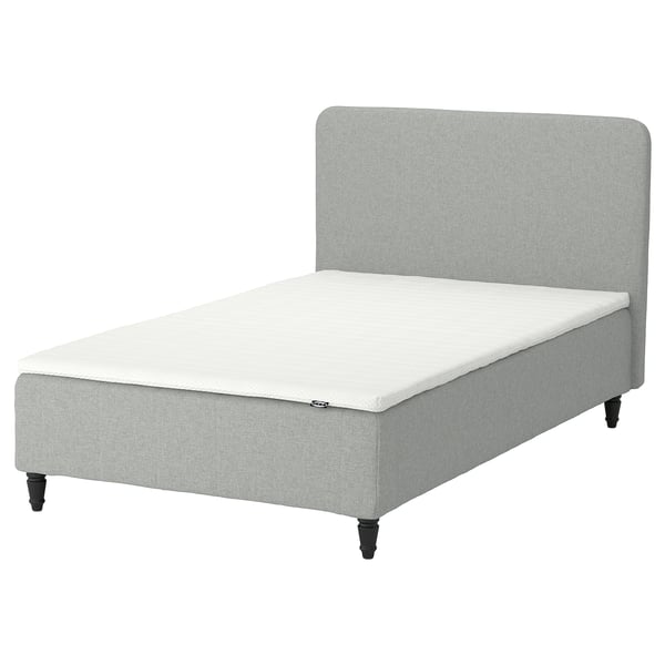 Minimalist modern bed. Upholstered headboard and base. Light grey fabric. Four dark wooden legs. No frame visible.
