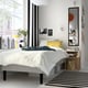 Modern bedroom with RENFJÄLLET bed, white grid bedspread, yellow pillows. Black mirrors, striped rug, bedside table, bag, city view windows.
