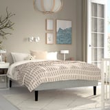 Neutral bedroom with RENFJÄLLET bed, chequered blanket, teddy bear, artwork, bedside table.