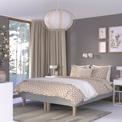 Gray bedroom with large bed, round light, plant, and artwork.