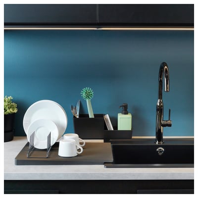 Modern kitchen sink with black faucet, white dishes, blue wall