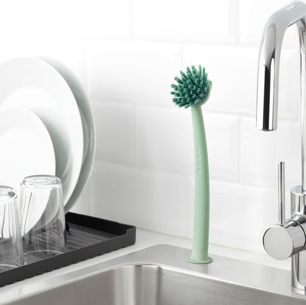 Green kitchen sink brush with suction base, sturdy bristles, scraper edge.