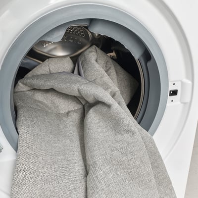 Gray fabric inside white washing machine with silver agitator.