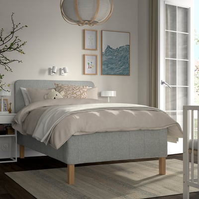 Grey RISHÖJDEN bed with comfy headboard, 7-zone mattress, by window, styled with decor.