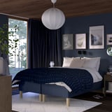 Blue bedroom with RISHÖJDEN bed, dark walls, white lamp, curtains, art, wooden nightstands, and white rug.