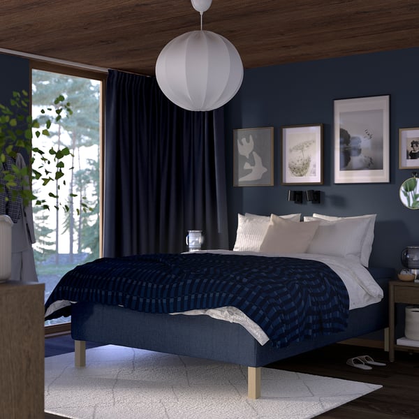 Modern bedroom with RISHÖJDEN bed, dark blue walls, white light. Beds pattern matches drapes, crisp white linens, pocket spring mattress.
