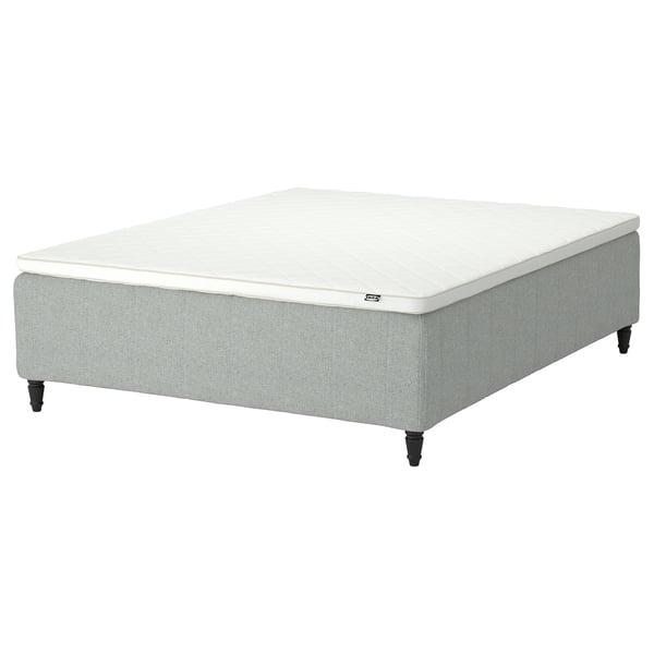 The IKEA RISHÖJDEN mattress in white and light grey, showcasing its rectangular shape, upholstered sides, and dark wooden legs.