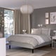 Gray bedroom with RISHÖJDEN bed, lamp, gray bedding, curtains, art, wooden floors.