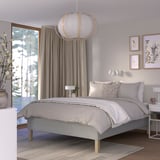 Minimalist bedroom with RISHÖJDEN bed, pendant lamp, grey curtains, rug, nightstands, and wall art.