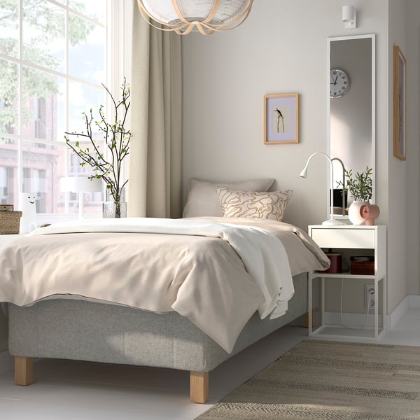 Modern bedroom with RISHÖJDEN bed, light bedding, large window, hanging light, nightstand with lamp and clock, art, plants.