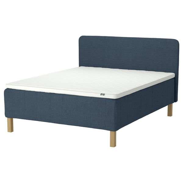 Blue upholstered bed with wooden legs, white mattress, modern design.