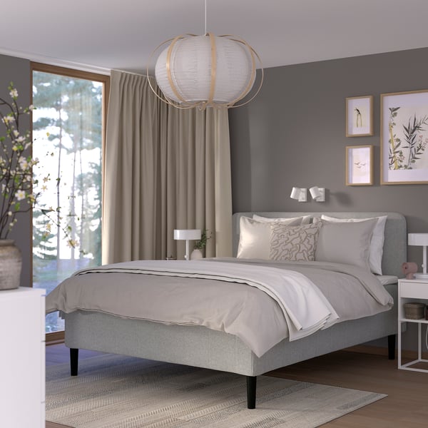 Modern bedroom with gray RISHÖJDEN bed, soft headboard, sturdy legs, neutral bedding, pendant lamp, and window with beige curtains.