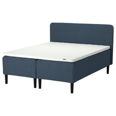 A modern queen bed with a blue fabric headboard and base, featuring a white mattress with a foam layer.