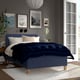 Blue RISHÖJDEN bed with pillows & blanket against gray wall, art, mirror, lamp & books on nightstand, large rug, french door.