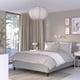Elegant bedroom with RISHÖJDEN bed, light gray bedding, stylish lamp, beige curtains, plant, and art.