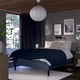 Modern RISHÖJDEN bed with 7 comfort zones, dark blue cover. Centrepiece in a cosy room with art, curtains, and rug.