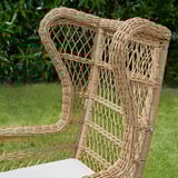 Wicker chair with intricate weaving, high back. Comfortable, weather-resistant, durable outdoor seating.