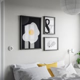 Modern white bedroom with minimalist art frames, mustard pillow.