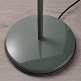 Modern green floor lamp base with reflective surface on wooden floor.