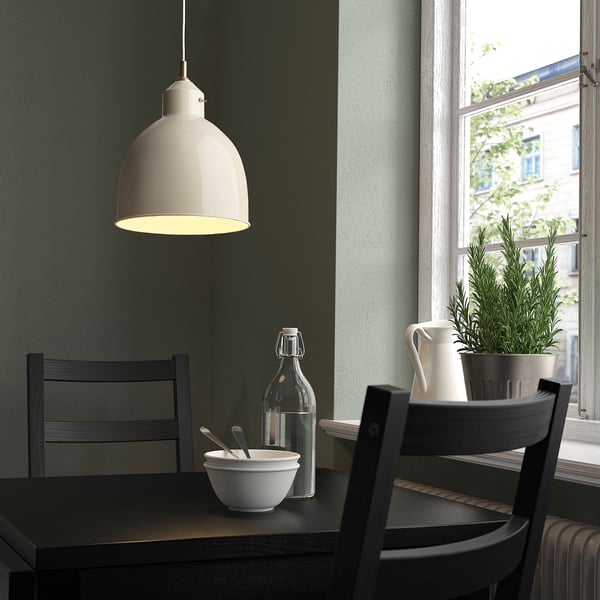 Small white RÖDFLIK lamp hangs near a window, illuminating a dark table with chairs and decor.