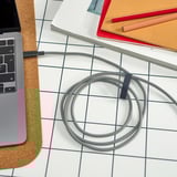 Image shows a coiled usb-c charging cable on a desk with a laptop and notebooks.