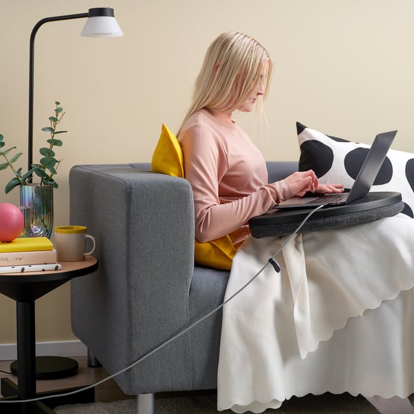 Woman working on laptop in armchair, lit usb-c cable