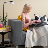 Woman working on laptop in armchair, lit usb-c cable