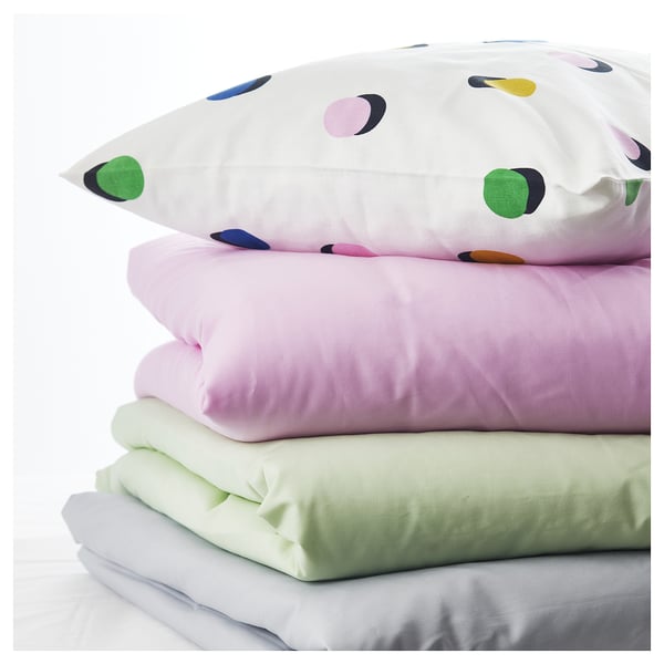 Stacked pillows: one with colorful dots, others in pastel shades.