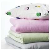 Stacked pillows: one with colorful dots, others in pastel shades.