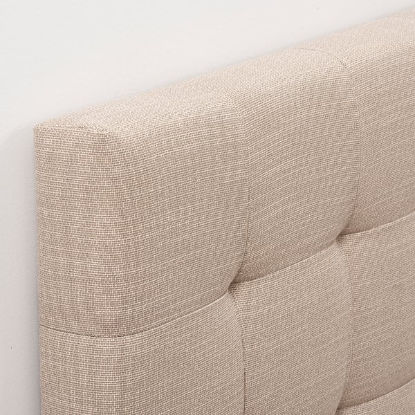Upholstered headboard corner, soft fabric with visible stitching.