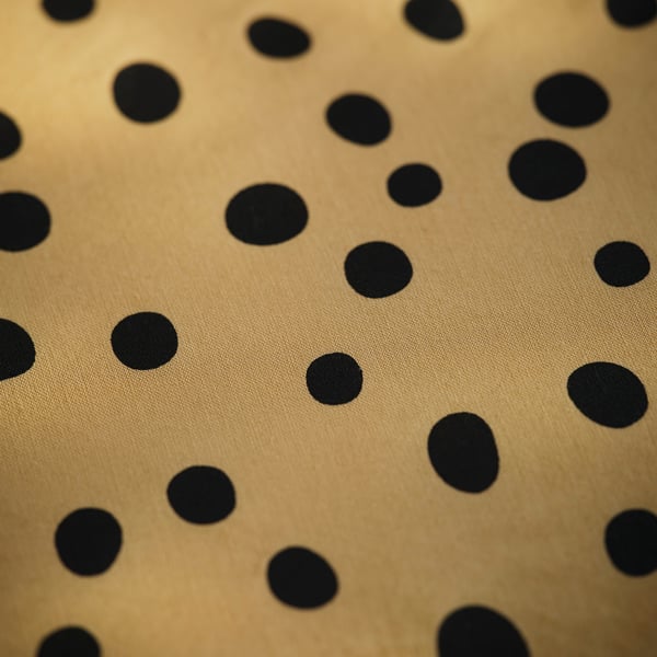 Polka-dot fitted sheet in golden color, smooth texture, evenly spaced black dots.