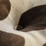 Soft, textured fabrics in beige, black, and brown. Close-up shows plush material quality.