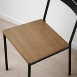 Square wooden table top with black metal legs on a wooden floor.
